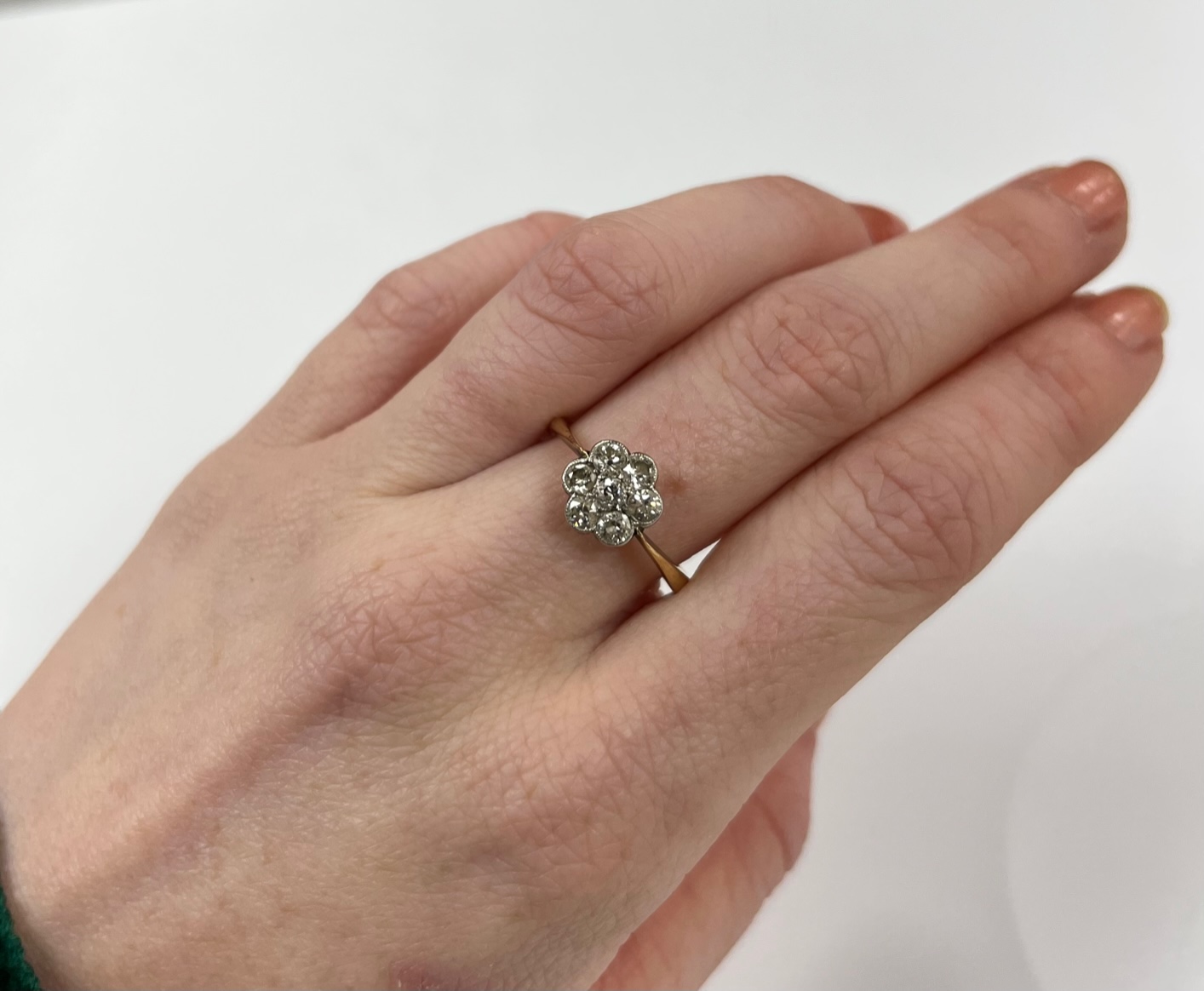 An 18ct and seven stone diamond set flower head cluster ring, size M/N, gross weight 2.9 grams.